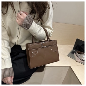 Close-up of brown vintage handbag with silver rivets and decorative buckle strap