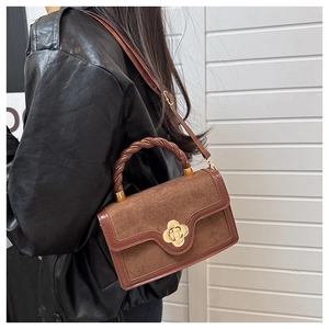 Brown retro crossbody bag with braided handle and gold floral twist lock on a model