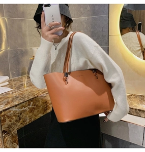 Braune Tragetasche aus Kunstleder mit FASHION Aufdruck getragen in stilvollem Ambiente
