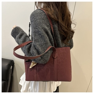 Detail of burgundy leopard embossed tote bag with decorative silk scarf on shoulder strap