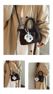 Detail of dark brown matte leather handbag featuring white stitching and plush dog charm