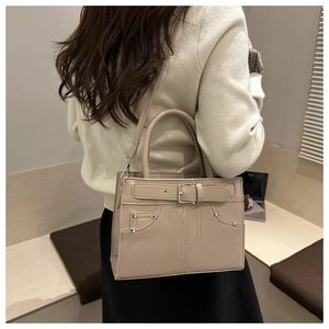 Detail of beige faux leather handbag with buckle, rivets and pocket stitching
