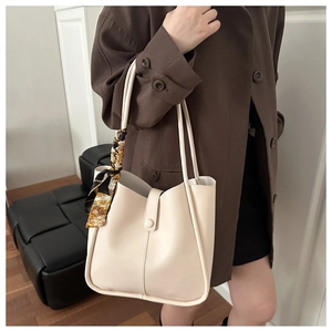 Chic cream leather tote bag with vintage floral scarf detail worn over a dark trench coat