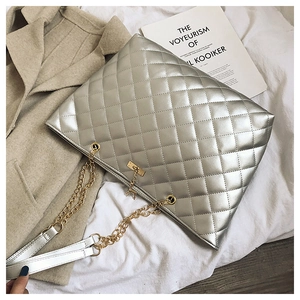 Detail of silver quilted handbag with golden deer charm and elegant metal chain strap