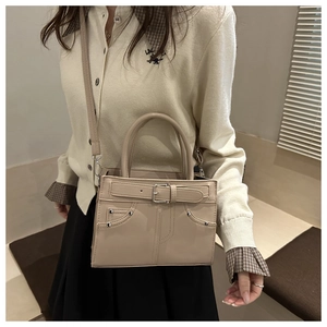 Close-up of beige PU leather handbag featuring buckle detail and metallic studs