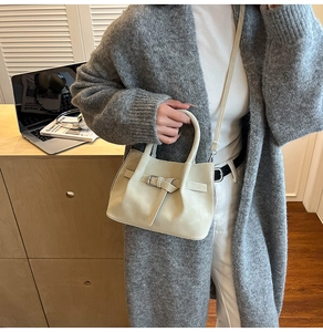 Vue détaillée du sac seau beige porté par un mannequin dans un style minimaliste