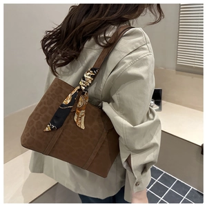 Detail of dark brown tote bag with leopard embossing and decorative silk scarf on handle