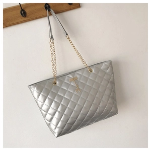 Detail of silver quilted tote bag with gold chain strap and metal deer pendant