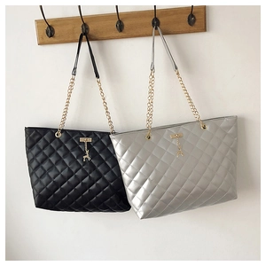 Close-up of quilted tote bags with gold chain straps and metal deer charms on hooks