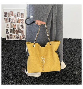 Detailansicht der gelben Tragetasche mit goldener Kette und Fransenanhänger für Damen