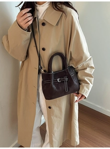 Détail du sac bandoulière en cuir marron foncé avec surpiqûres blanches et boucle