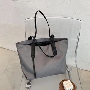 Minimalistische grijze grote shopper tas met zwarte riemen op een moderne stoel