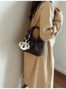 Détail du sac seau marron foncé avec coutures blanches et breloque chien peluche