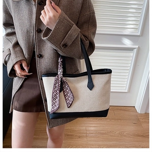 Detail of canvas tote bag with black leather trim and decorative patterned silk scarf