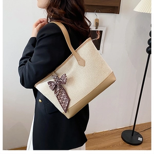 Detail of canvas tote bag with contrast faux leather trim and decorative silk scarf accessory