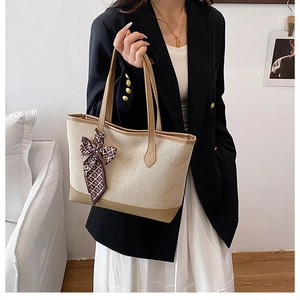 Detail of canvas tote bag with brown leather trim and decorative patterned scarf accessory