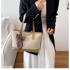 Detail of large canvas tote bag with brown leather trim and decorative printed silk scarf