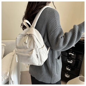 Close-up of off-white corduroy backpack with woven rope zipper and fashion tag