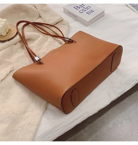 Detailansicht der großen braunen Ledershopper mit Fashion-Prägung auf dem Bett