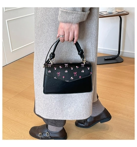 Black leather handbag with pink floral bow prints and twisted handle detail for women