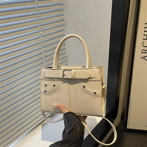 Chic beige handbag featuring creative denim-style waist belt and metallic stud accents