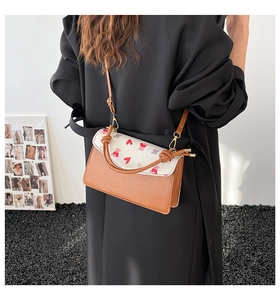 Detail view of a compact crossbody bag with bear prints worn by a model in a modern studio