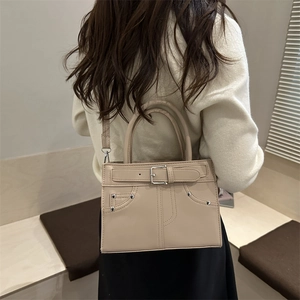 Sac à main minimaliste beige en similicuir avec boucle et clous porté par un mannequin