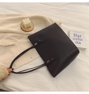 Detaillierte Draufsicht einer schwarzen minimalistischen Tragetasche auf einem Bett