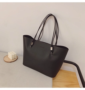 Detail der mattschwarzen Leder-Einkaufstasche mit minimalistischer FASHION-Prägung