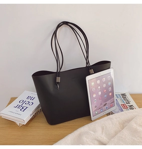 Detailansicht der großen schwarzen Tragetasche mit FASHION-Schriftzug neben Büchern