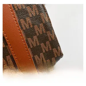 Macro shot of monogram canvas fabric with premium brown leather trim and orange stitching