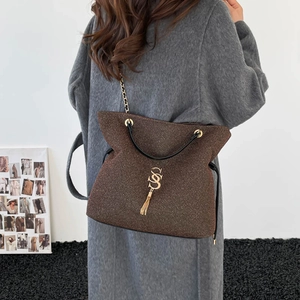 Sac cabas marron à paillettes avec logo SS doré et franges porté par un mannequin