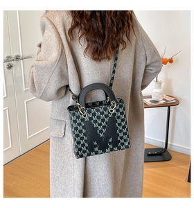 Detailed view of embroidery pattern and gold hardware on large tote bag shown on model