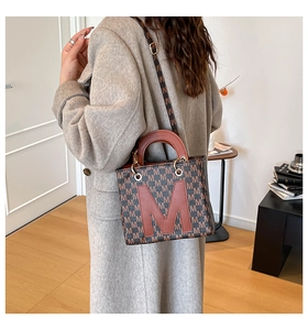 Detail of a chic canvas tote bag with M-letter pattern on a grey wool coat back-view