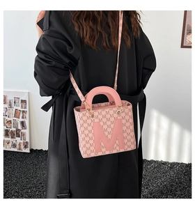 Rear view of a model carrying a pink monogrammed tote bag with a wide crossbody strap