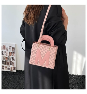 Chic pink tote bag with letter print pattern and top handles shown on model shoulder