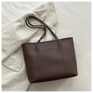 Detail of dark brown tote bag showing the lychee grain texture and leather logo stamp