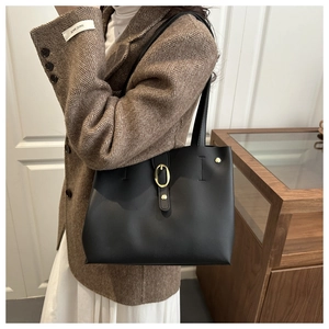 Dettaglio borsa tote in pelle nera con fibbia dorata e tracolla sottile in pelle