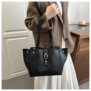 Dettaglio della borsa tote in ecopelle nera con fibbia dorata e rivetti metallici