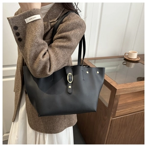 Dettaglio borsa tote in pelle nera con elegante fibbia dorata e sottili spalline