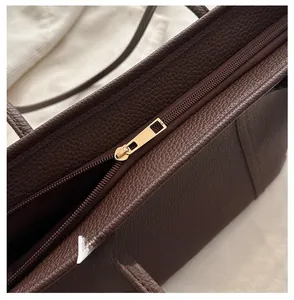 Detailed close-up of premium gold zipper and dark brown pebble leather on tote bag