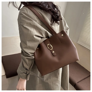 Dettaglio della borsa tote in pelle marrone con fibbia dorata e rivetti
