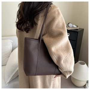Close-up of a vintage dark brown lychee grain leather tote bag with long shoulder straps