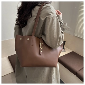 Dettaglio di una borsa tote in pelle marrone con fibbia dorata e rivetti sulla tracolla