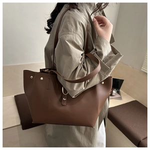 Grande borsa tote in pelle marrone con dettagli di borchie dorate indossata dal modello