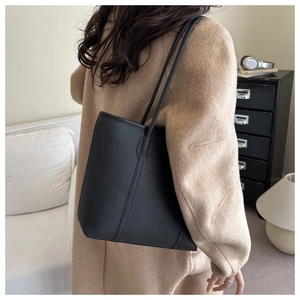 Close-up of black lychee grain leather tote bag with vertical stitching and slim straps