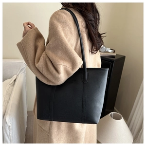 Close-up of black litchi pattern tote bag with fine straps and vertical stitching detail