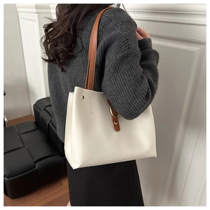 Vista laterale di una borsa shopper beige con tracolla marrone per un look moderno