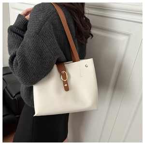 Detail of cream tote bag with brown straps and gold metal buckle on a model side view