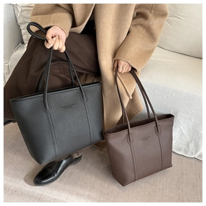 Detail of minimalist leather tote bags in black and brown with pebbled texture and stamp